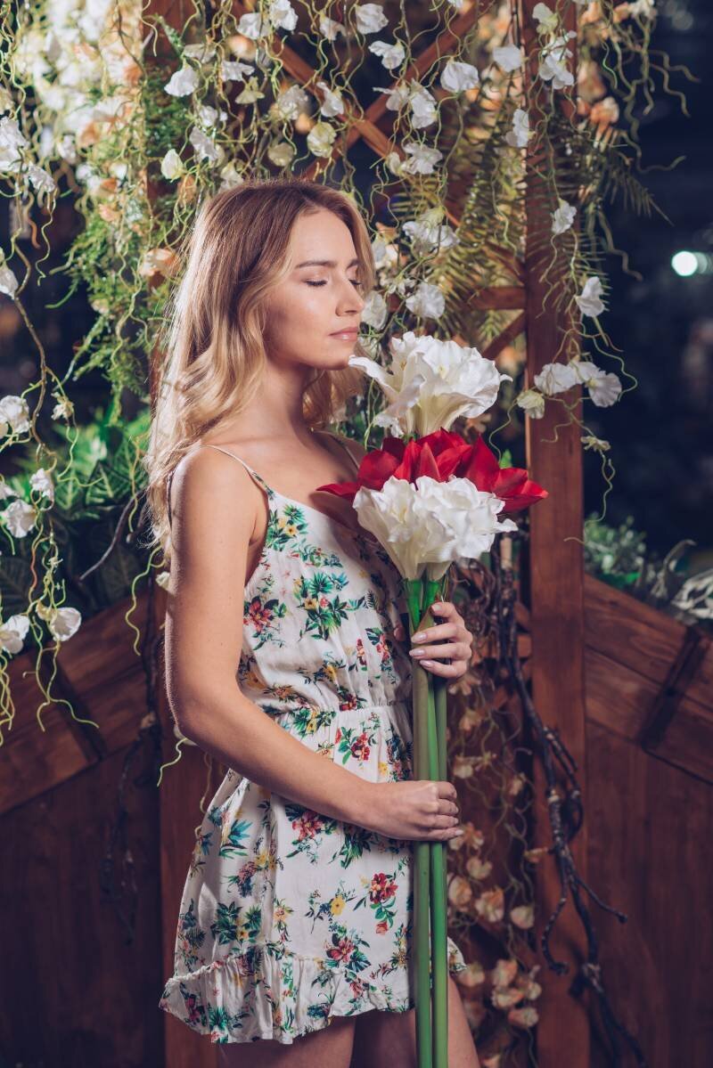 young-woman-holding-bunch-artificial-white-red-flowers-standing-garden