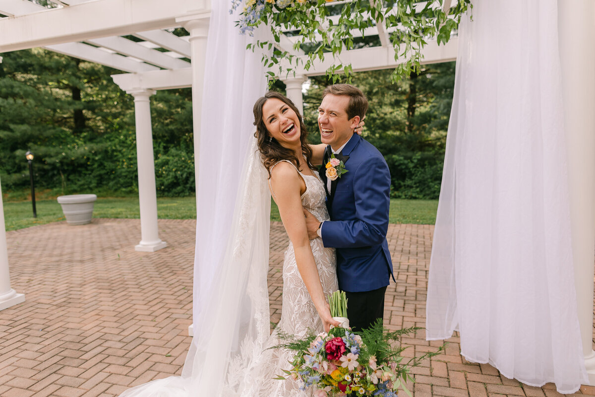 Wedding Photographer, A bride and groom laugh together outside on the patio