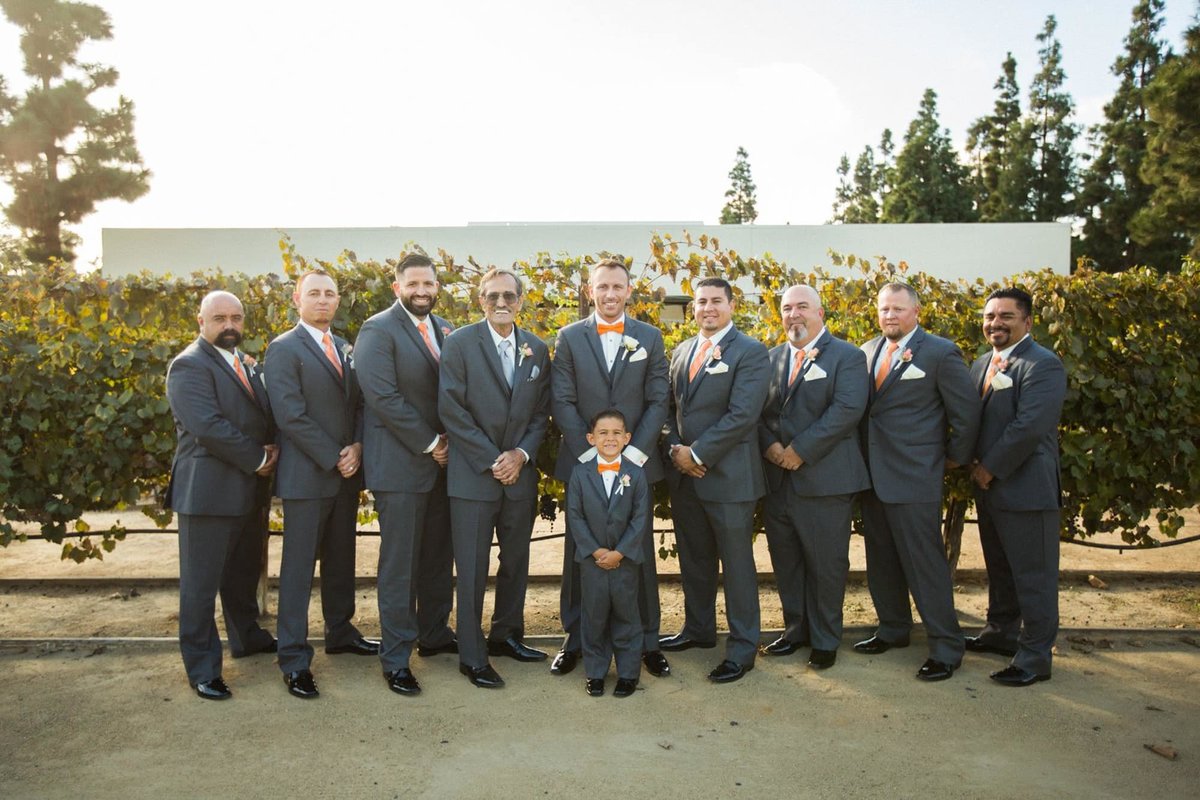 Groom poses with his Groomsmen all decked out in their gray suits