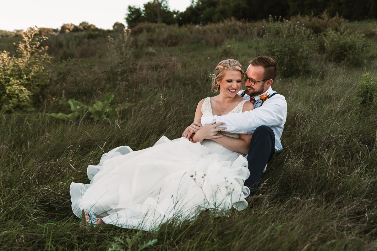 wedding couple snuggle in the tall grass