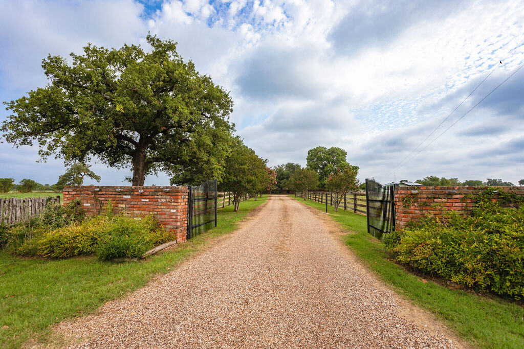 Driveway with gated entrance to this 5-bedroom, 4-bathroom vacation rental house for 16+ guests with pool, free wifi, guesthouse and game room just 20 minutes away from downtown Waco, TX.