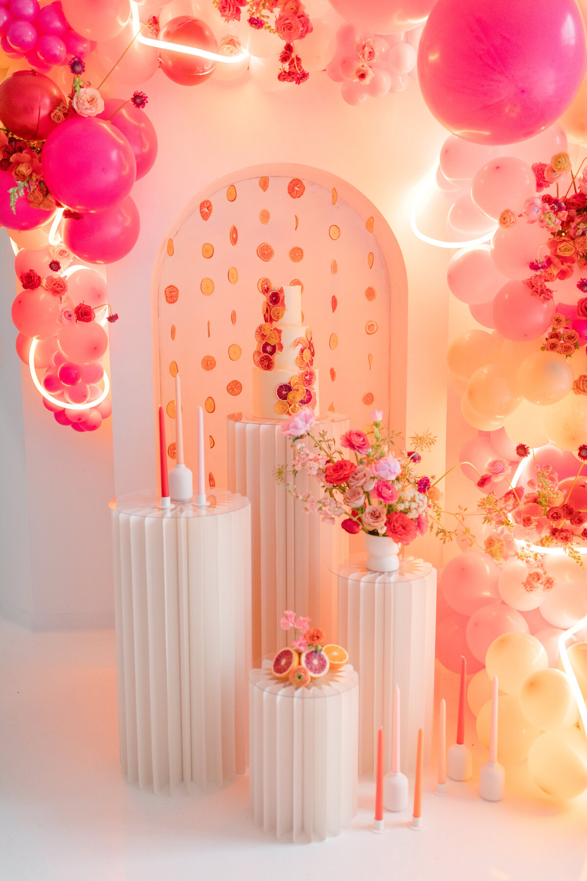 balloon arch surrounded cake and floral displays