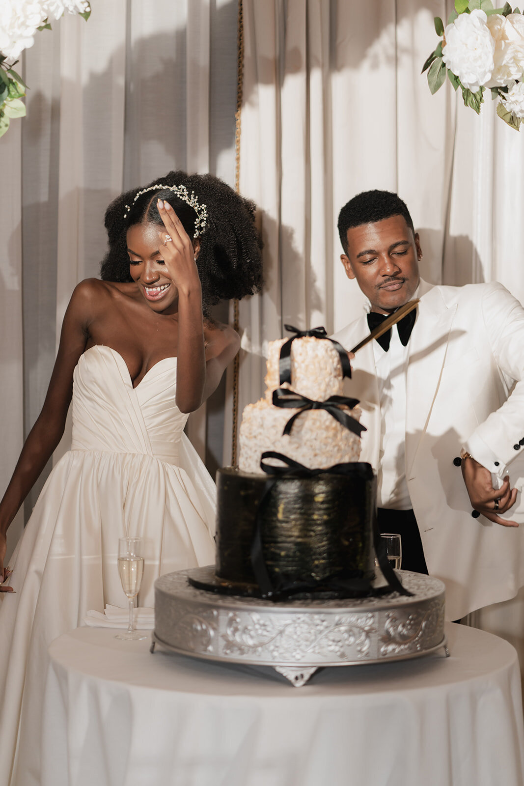black bride and grooom with black and white wedding cake with bows