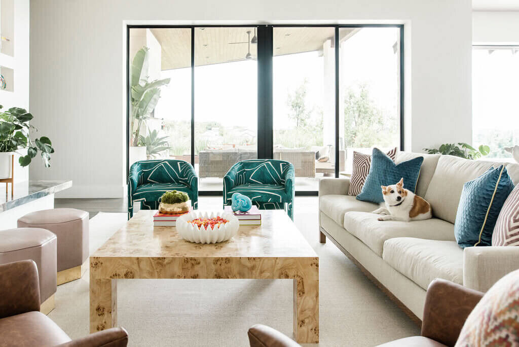 oyster creek studios austin barton creek wooden coffee table with turquoise chairs and ivory softa with dog in living room