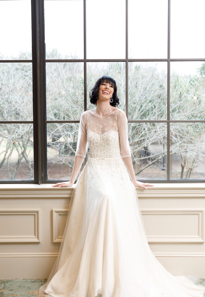 A model wears the Rei bridal style and models it in front of a window at the Hotel Bennett in downtown Charleston.