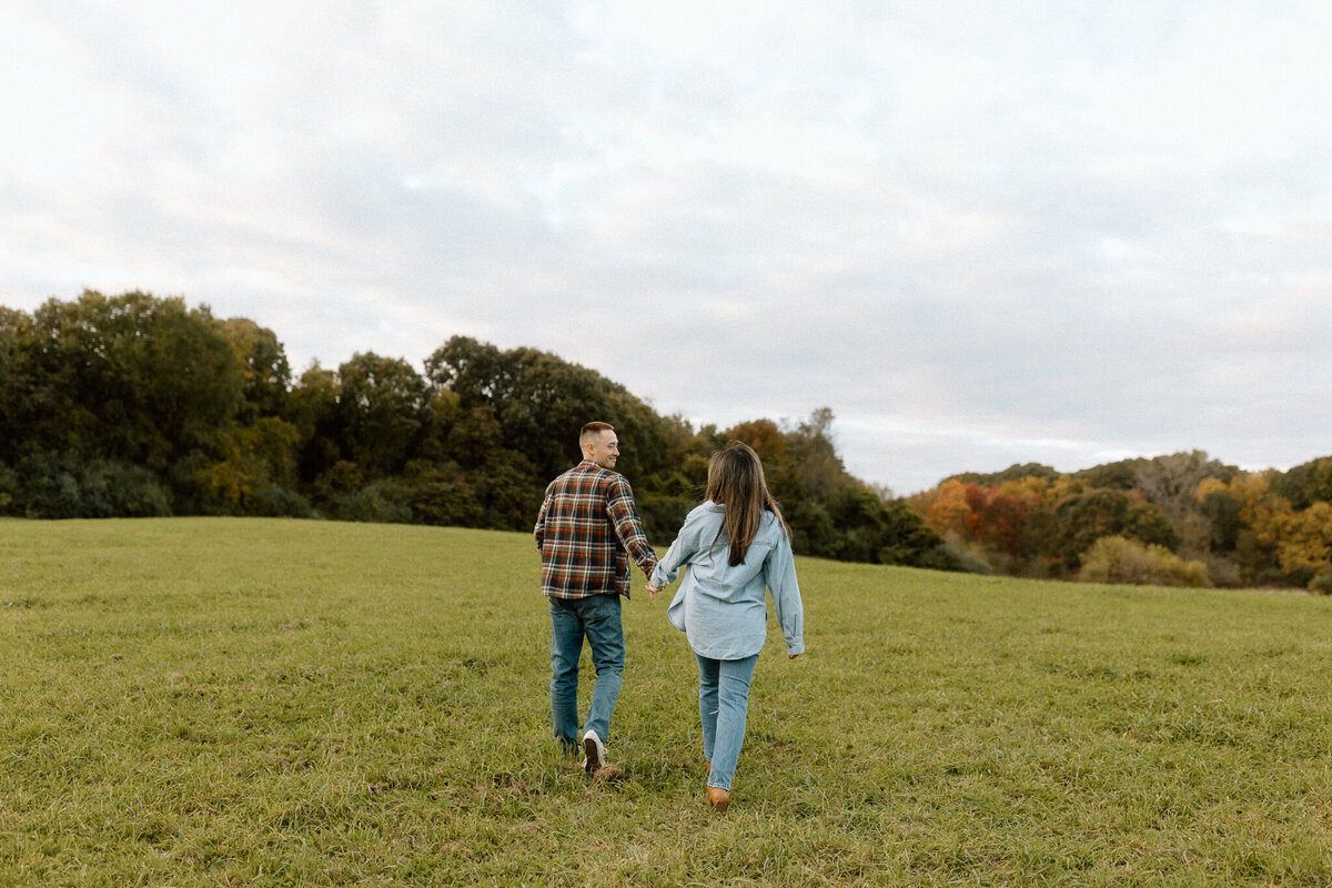 A couple holding hands and walking in an open field