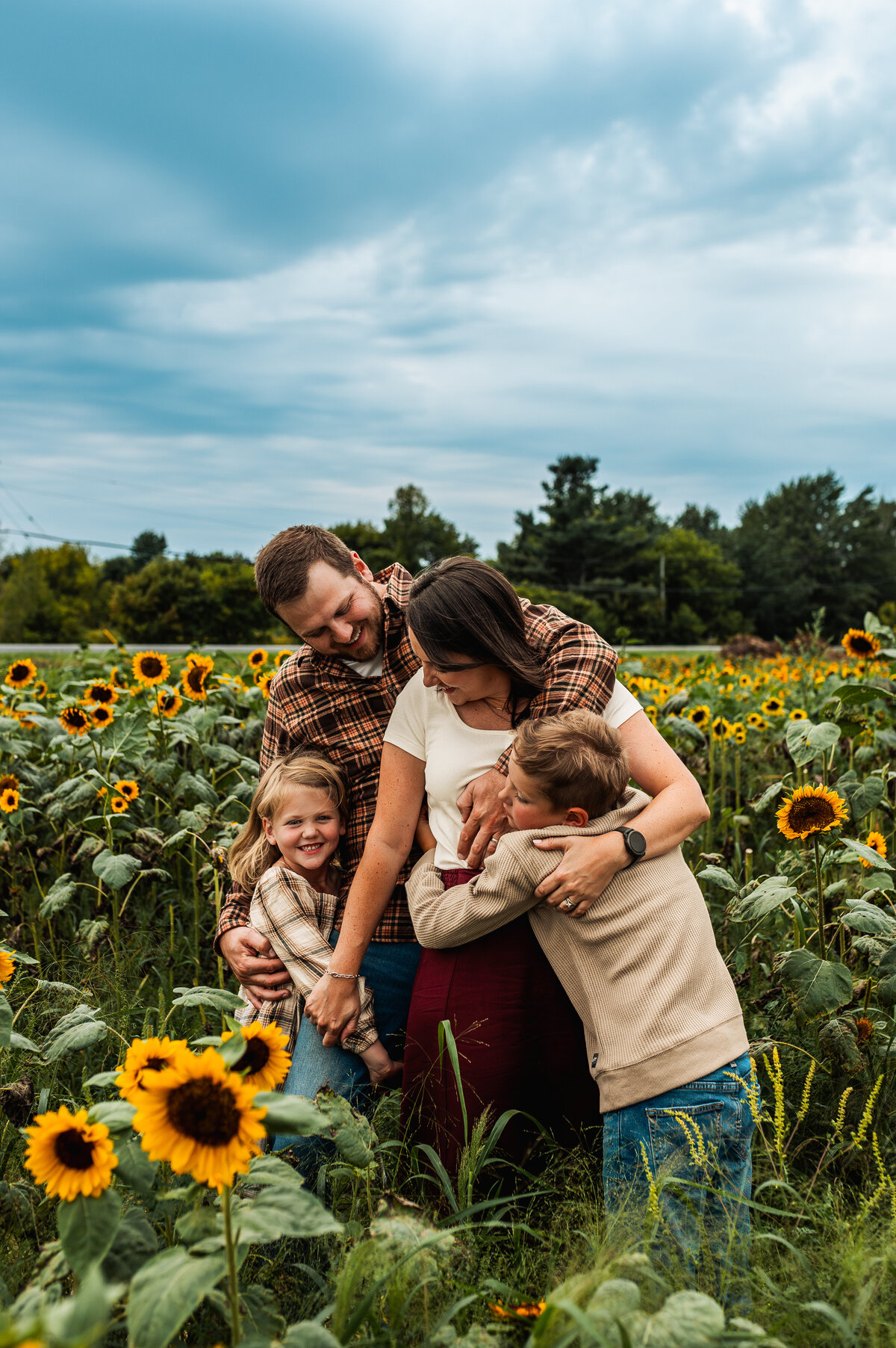 Family hugging in a sunflower field during Ottawa summer mini session.