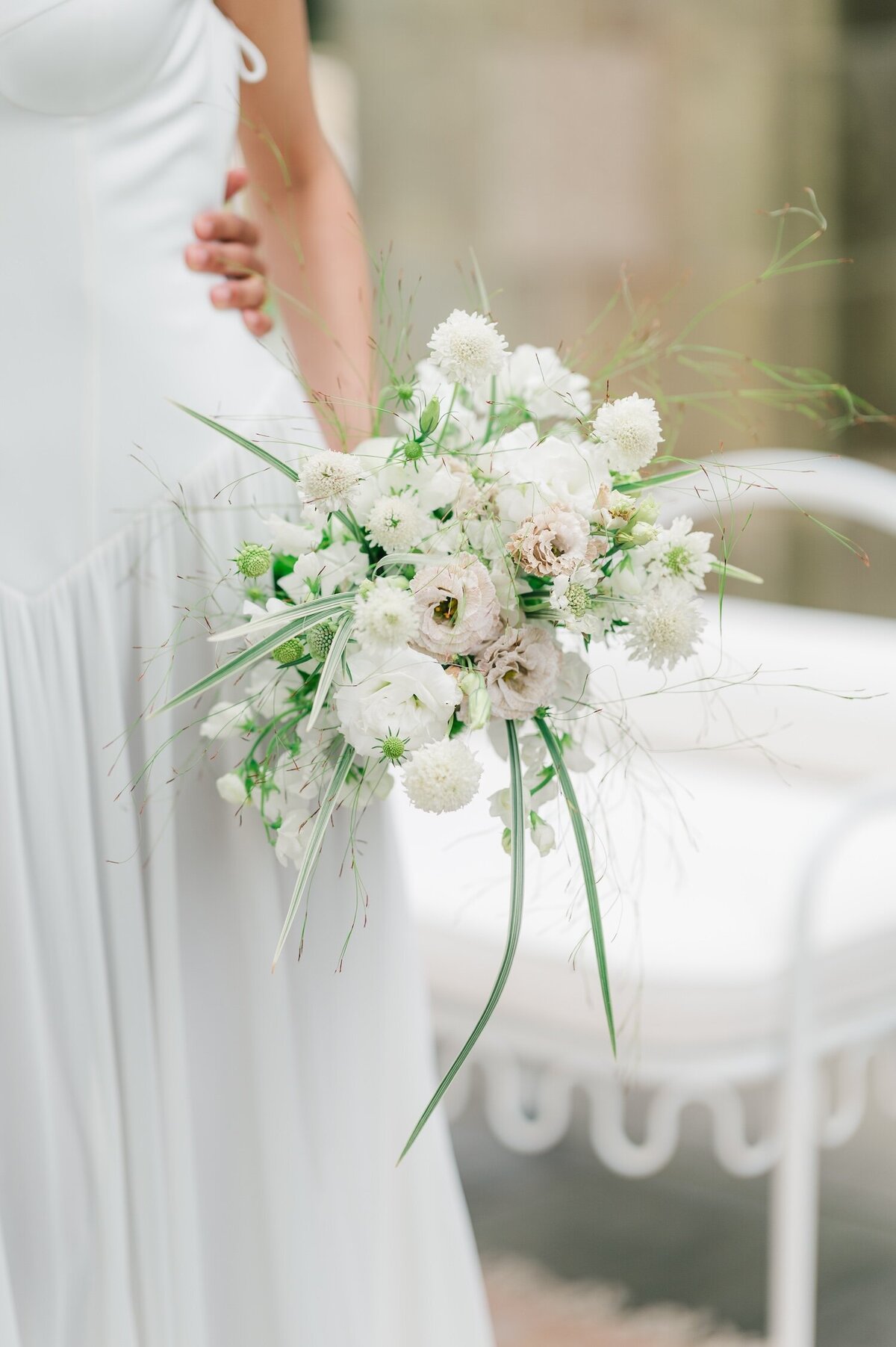 A whimsical pastel-colored bouquet being held by a bride. 
