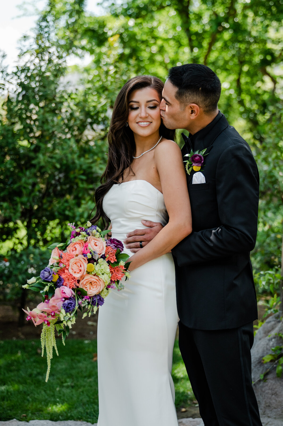 Groom kissing the bride's cheek at Hidden Hollow in Reedley, CA