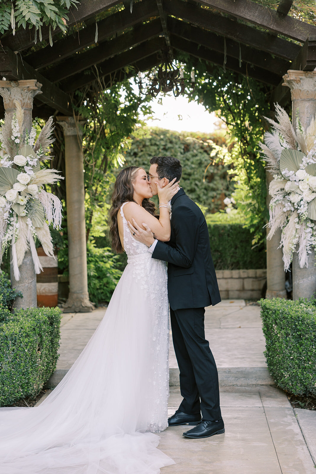 Bride and groom share their first kiss at the English Garden side at Wolf Lakes