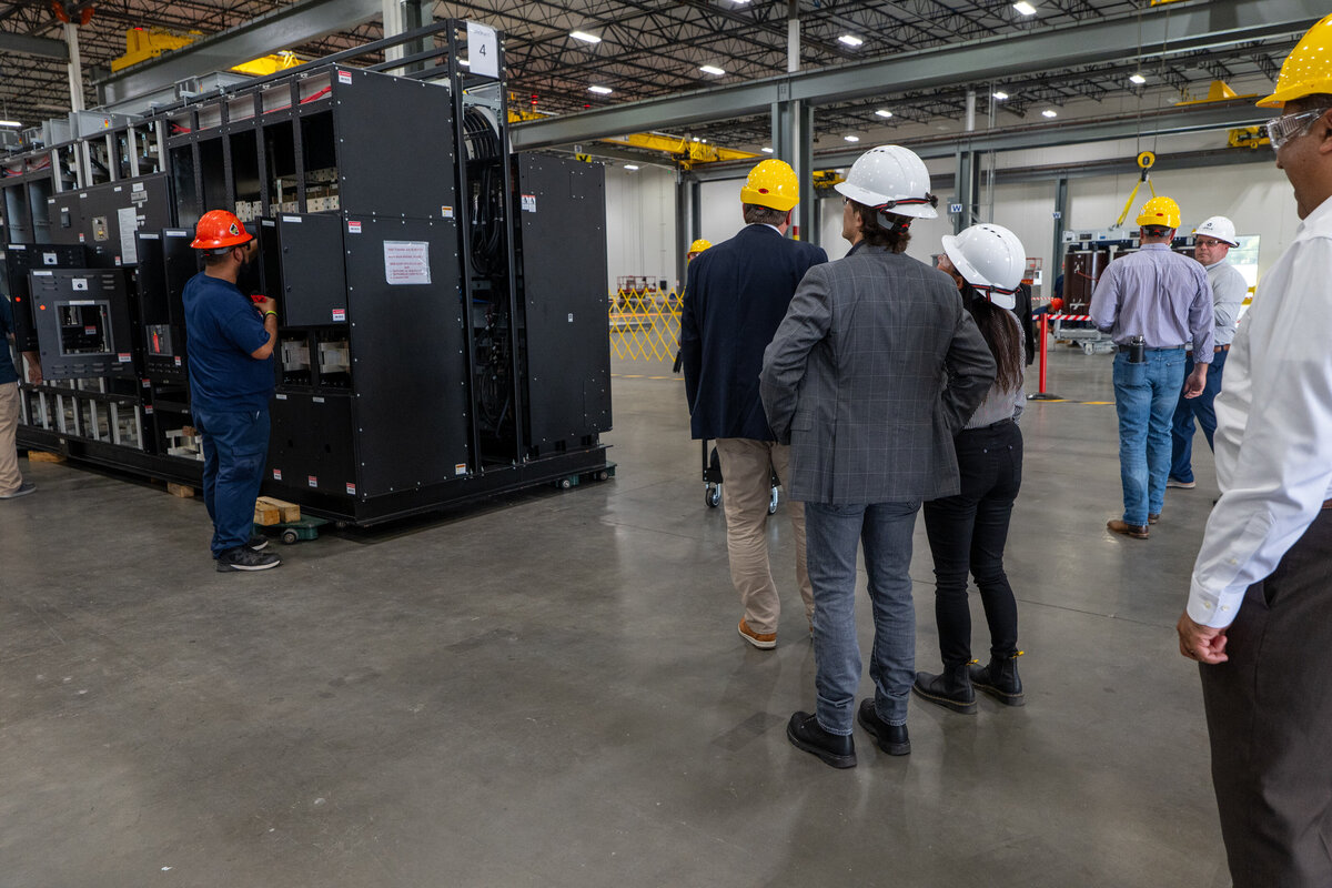 A group of people in hard hats touring a warehouse 