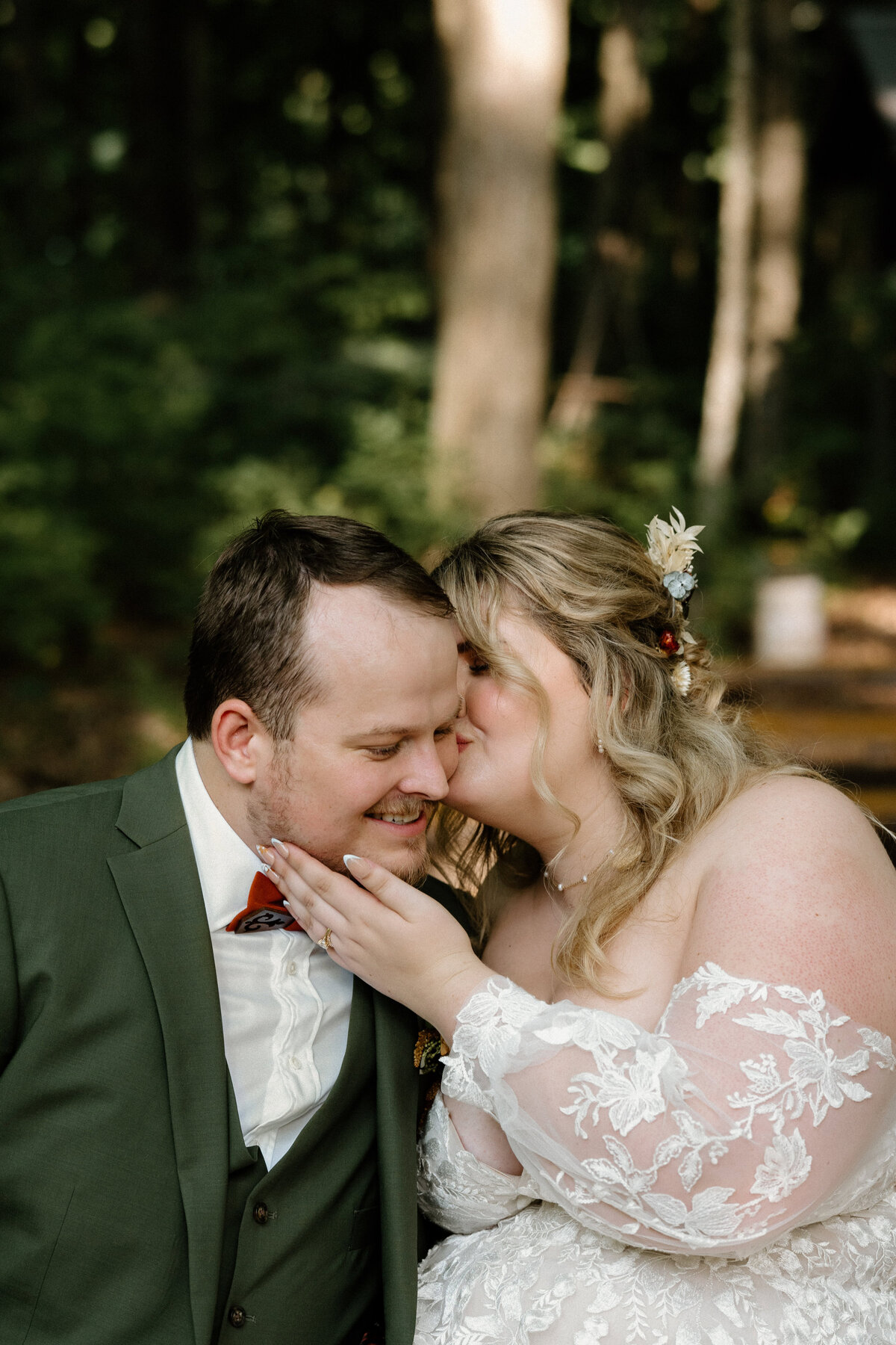 The groom smiling fondly as his bride kisses his cheek