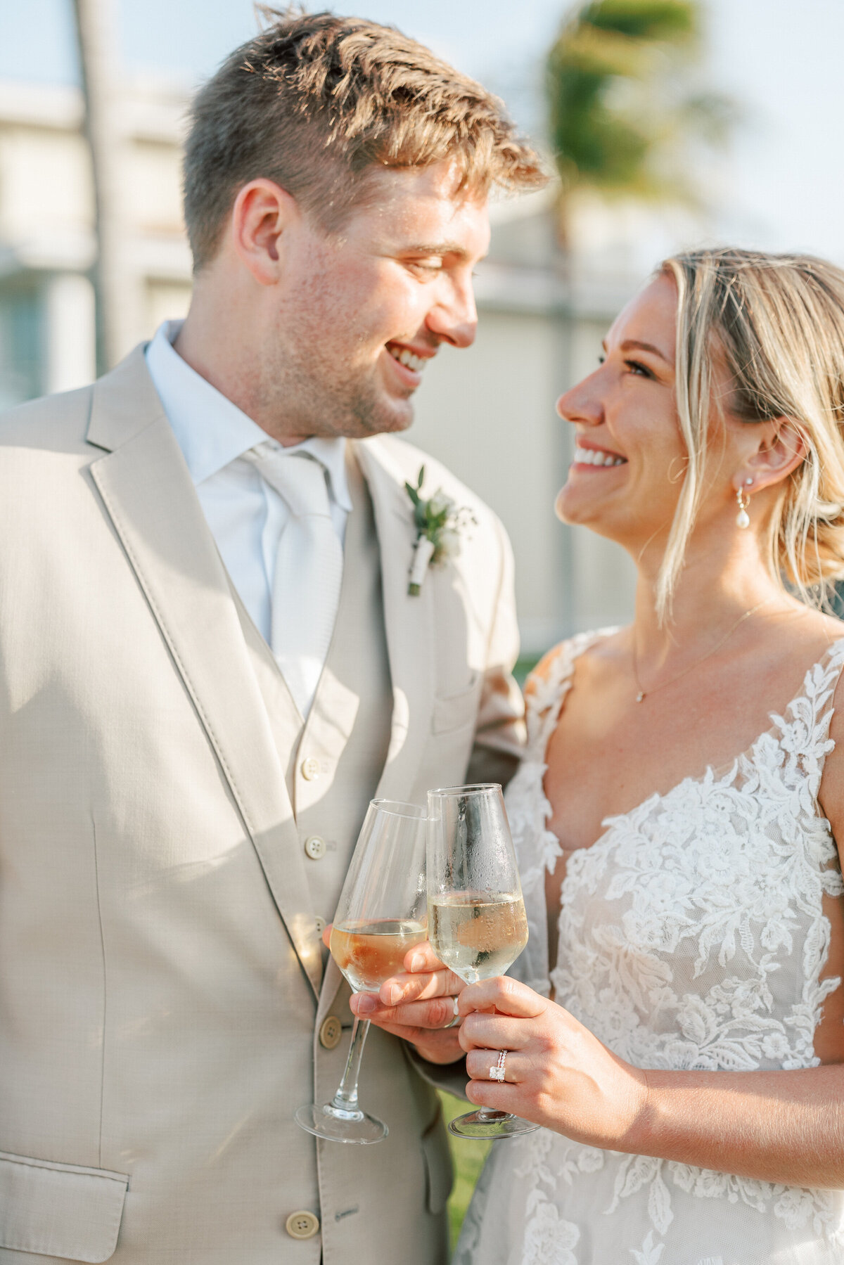 Bride and groom smile at each other while holding wine glasses during a Cancun wedding, captured by Philly photographer.