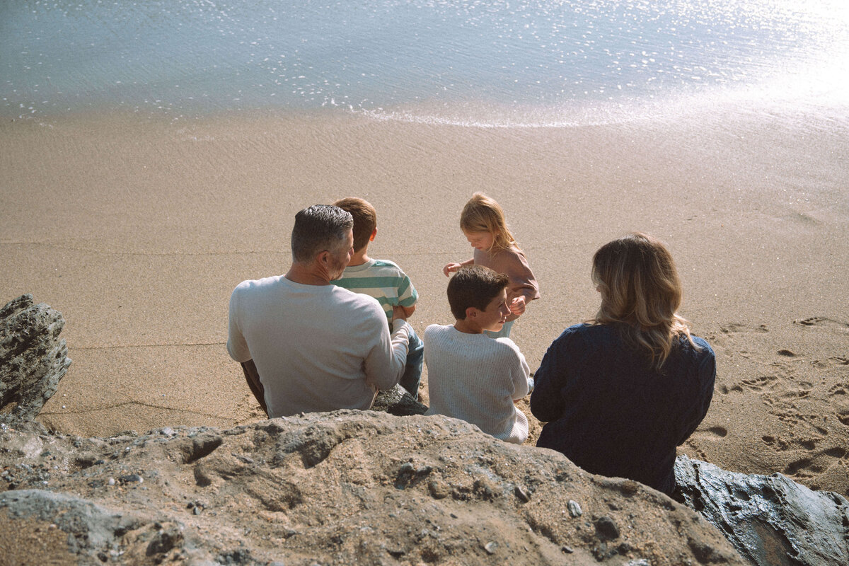 Family sitting on rocks overlooking the ocean during a Laguna Beach family photo session in Southern California