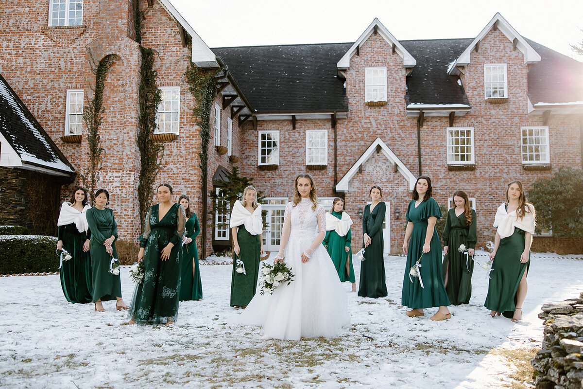 Bride and bridesmaids in snow in front of a mansion