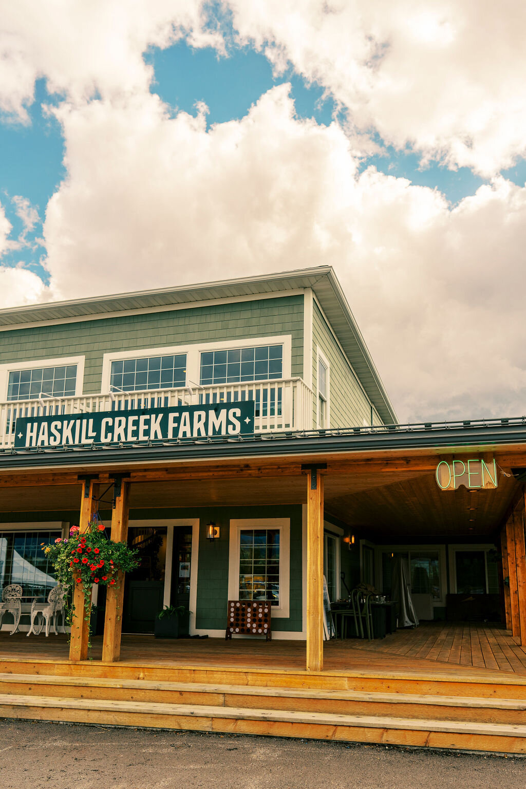 Front exterior of Haskill Creek Farms with a neon “OPEN” sign and hanging flower baskets, captured by Joseph Mayden for brand and location marketing photography.