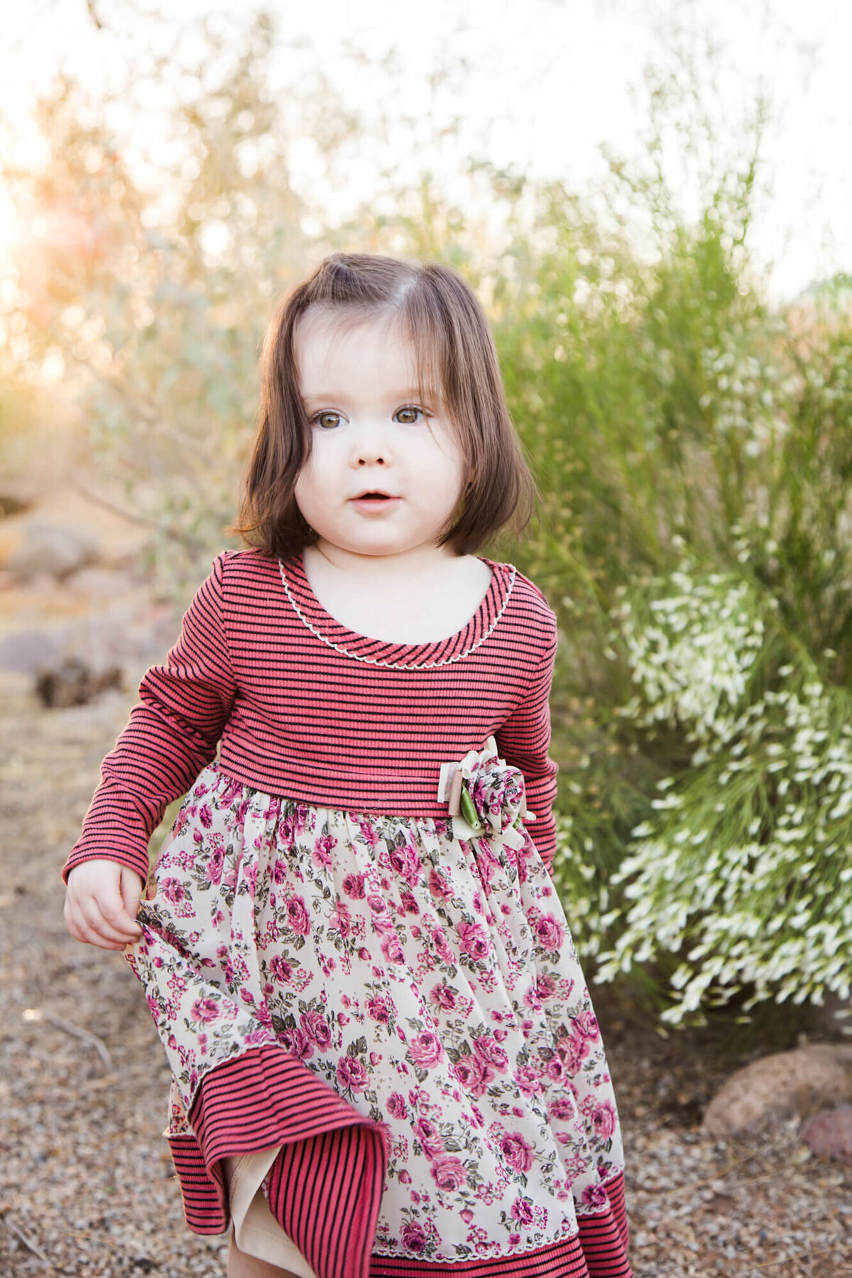 toddler girl in a red and flowered dress at a park