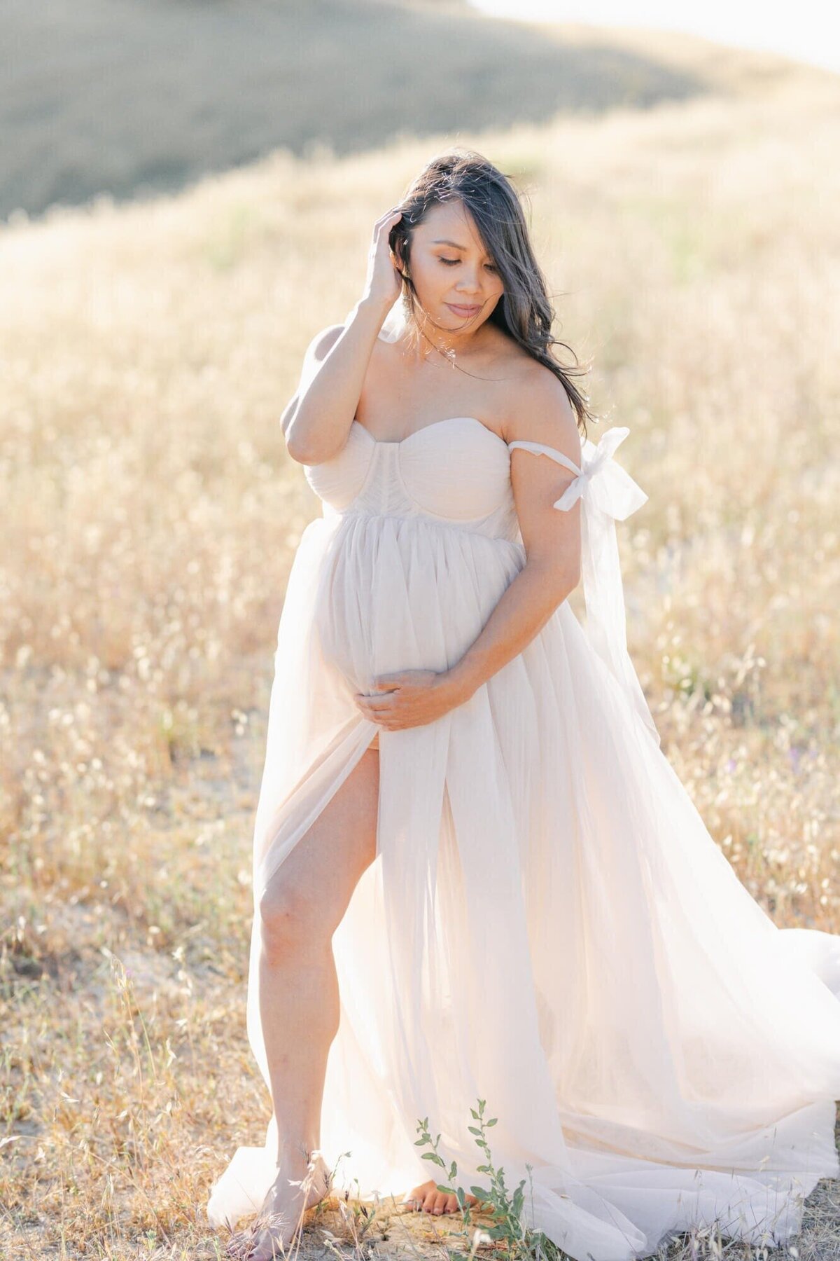 Pregnant woman framing her belly in a tulle dress taken by San Francisco Maternity Photographer Laurel Smith.