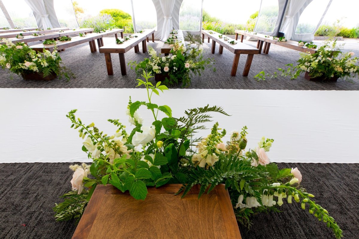 Wooden benches and greenery decor along aisle at wedding ceremony