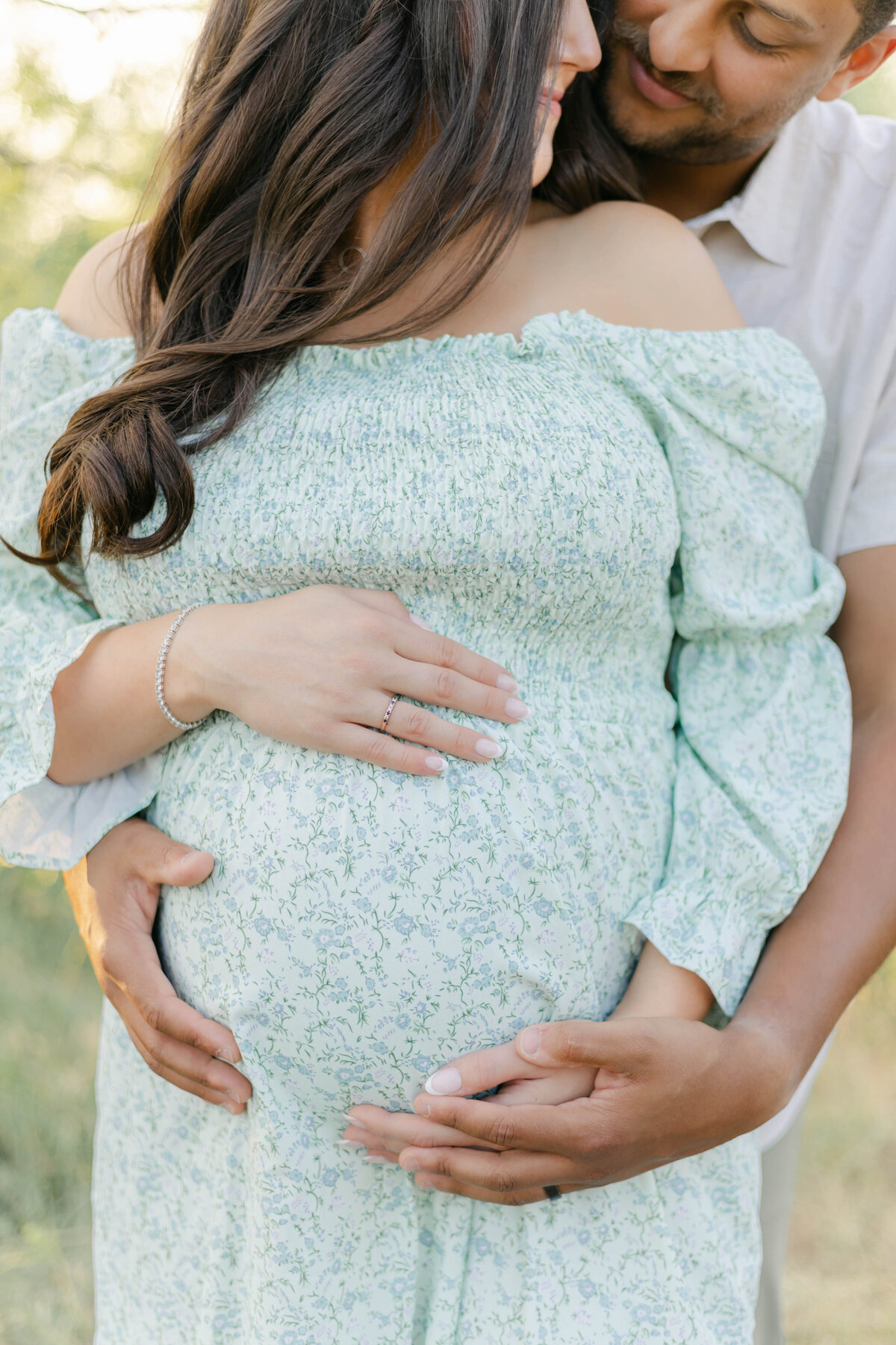 close up of a pregnant couple holding the baby bump and looking at each other
