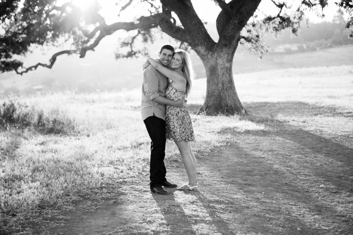 Young couple in love portraits engagement session; photography in front of tree in field