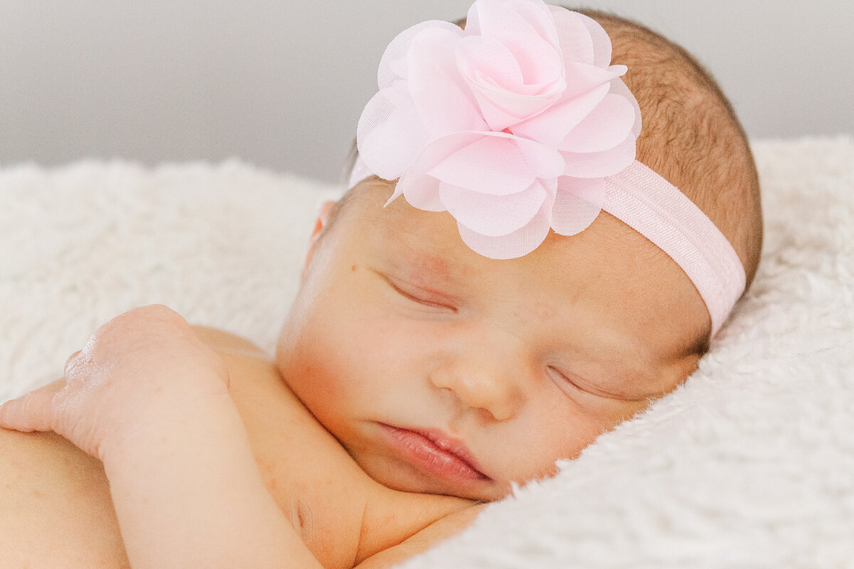 newborn baby in a pink bow sleeps