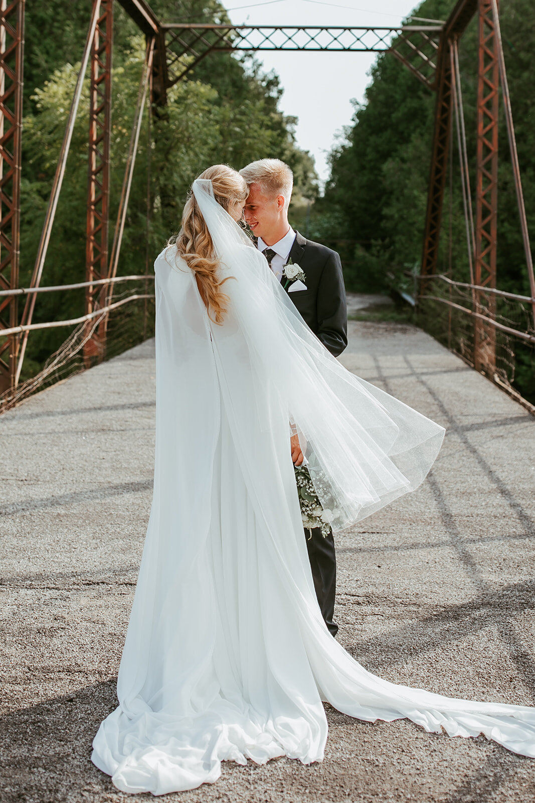 Newlyweds sharing a quiet moment at a bridge in Waterloo.
