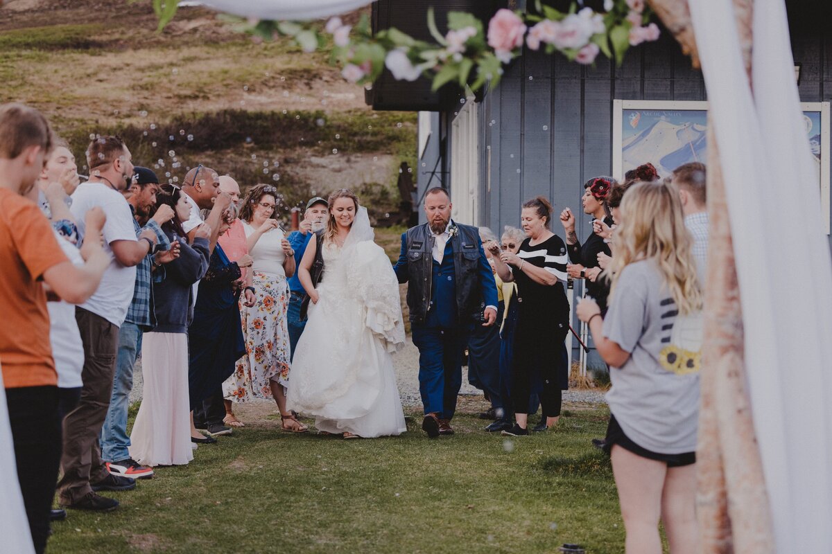 A couple makes their grand exit from their wedding  in their motorcycle club cuts
