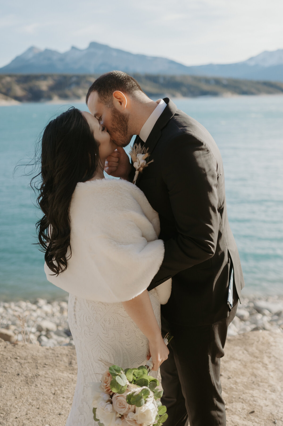 Destination wedding photograph of the couple kissing in front of lake