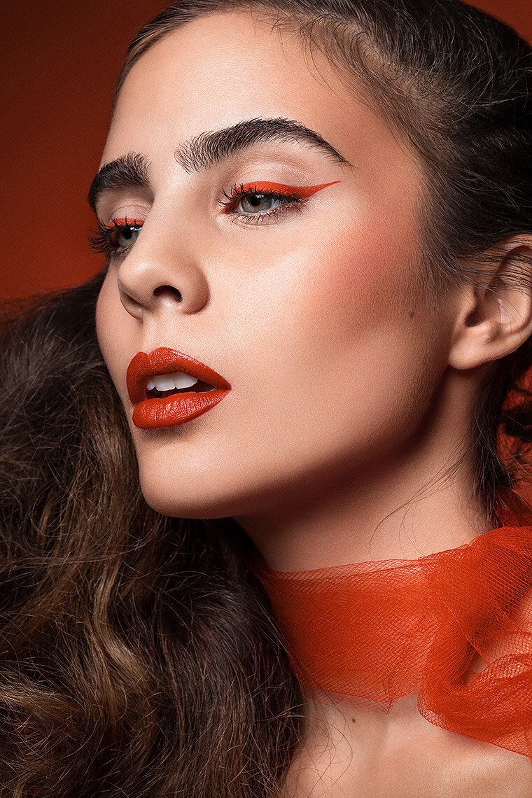 Striking portrait of Flor with voluminous hair and bold red makeup, captured by Ylva Erevall in dramatic lighting.