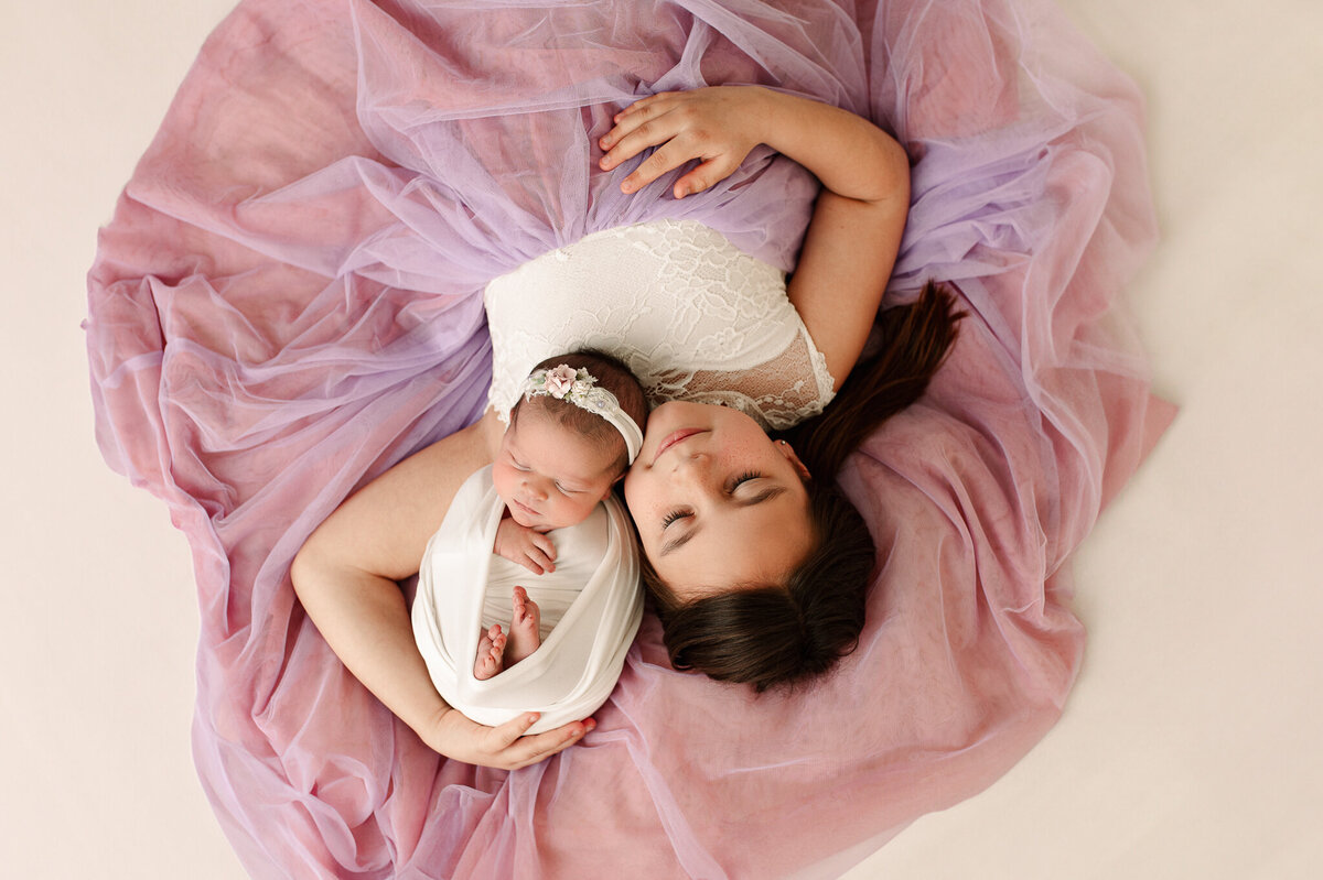 Newborn girl and big sister purple background sleeping photography