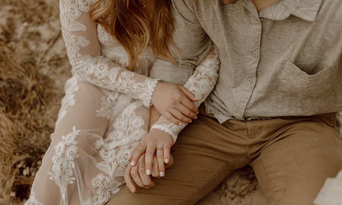 Couple holds hands showing off the engagement ring