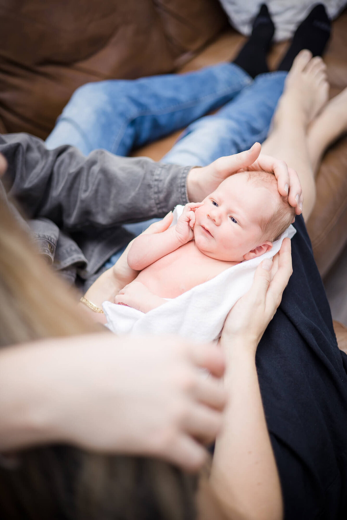 Las vegas newborn baby boy looking at his parents while they hold him on the couch