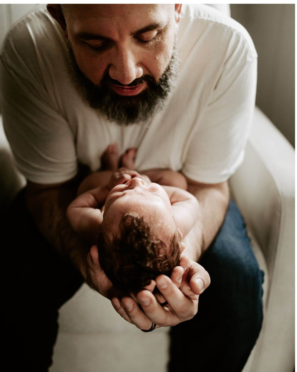 A bearded man cradling a baby in his arms poses for the Pittsburgh newborn photographer.