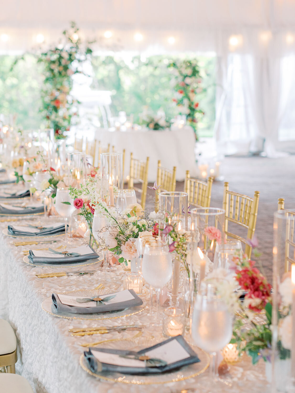 Long reception table with gold chairs and floral centerpieces