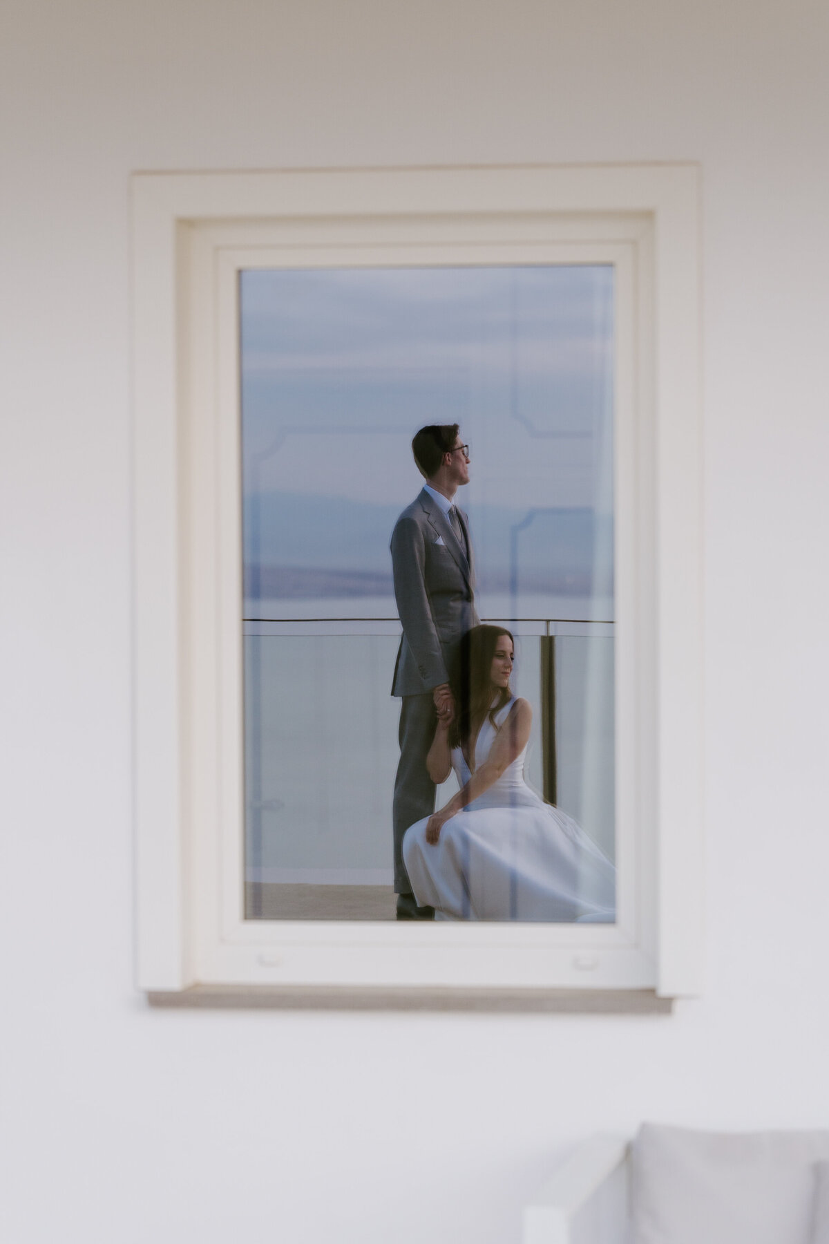 Couple reflected in window during intimate portrait moment