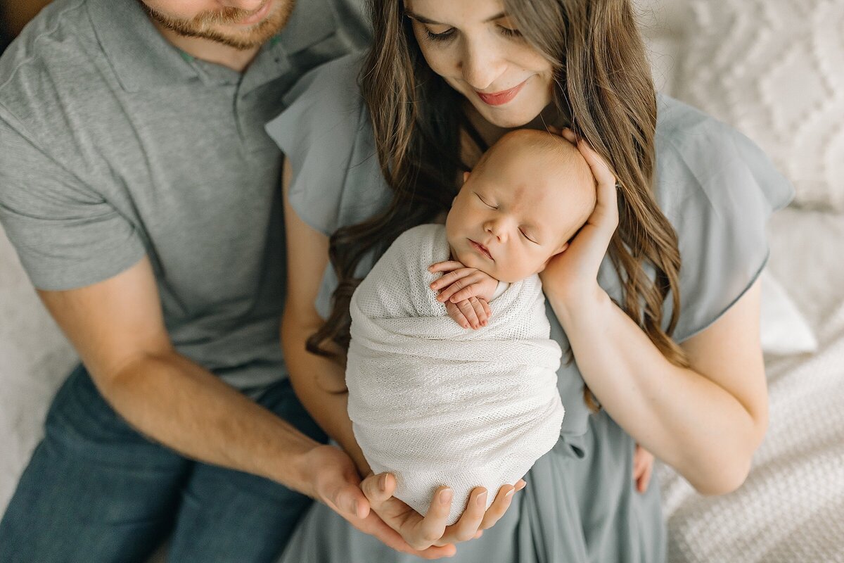 Mom and dad with newborn boy wrapped for photo sessions