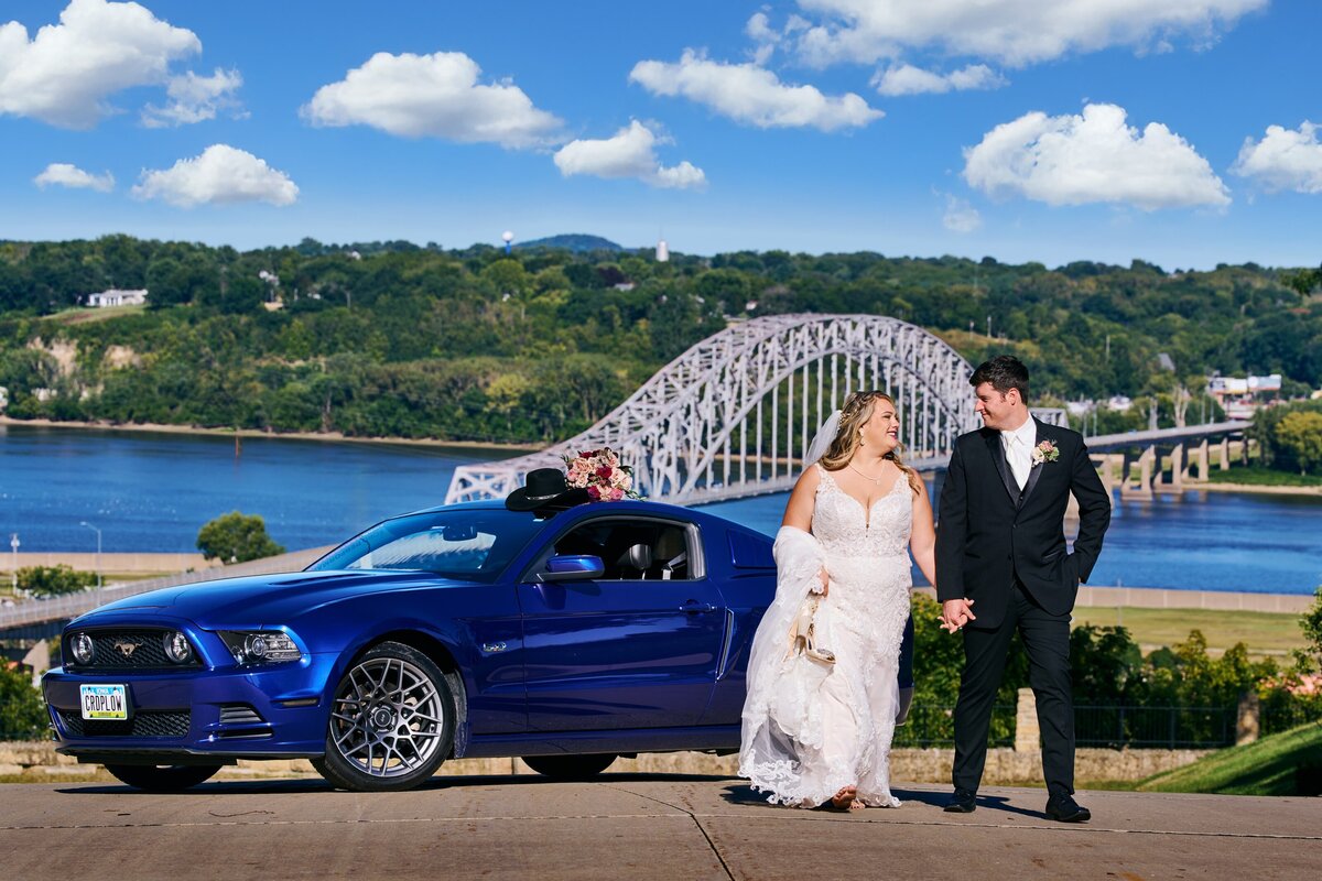 wedding couple with car over looking Dubuque Bridge