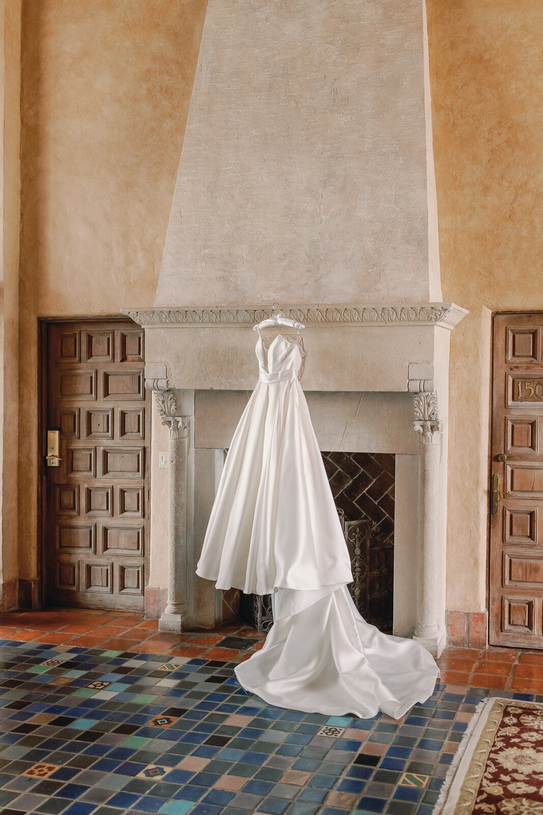Wedding dress hung on the fireplace in the suite at the Biltmore Coral Gables, Miami Wedding Photographer