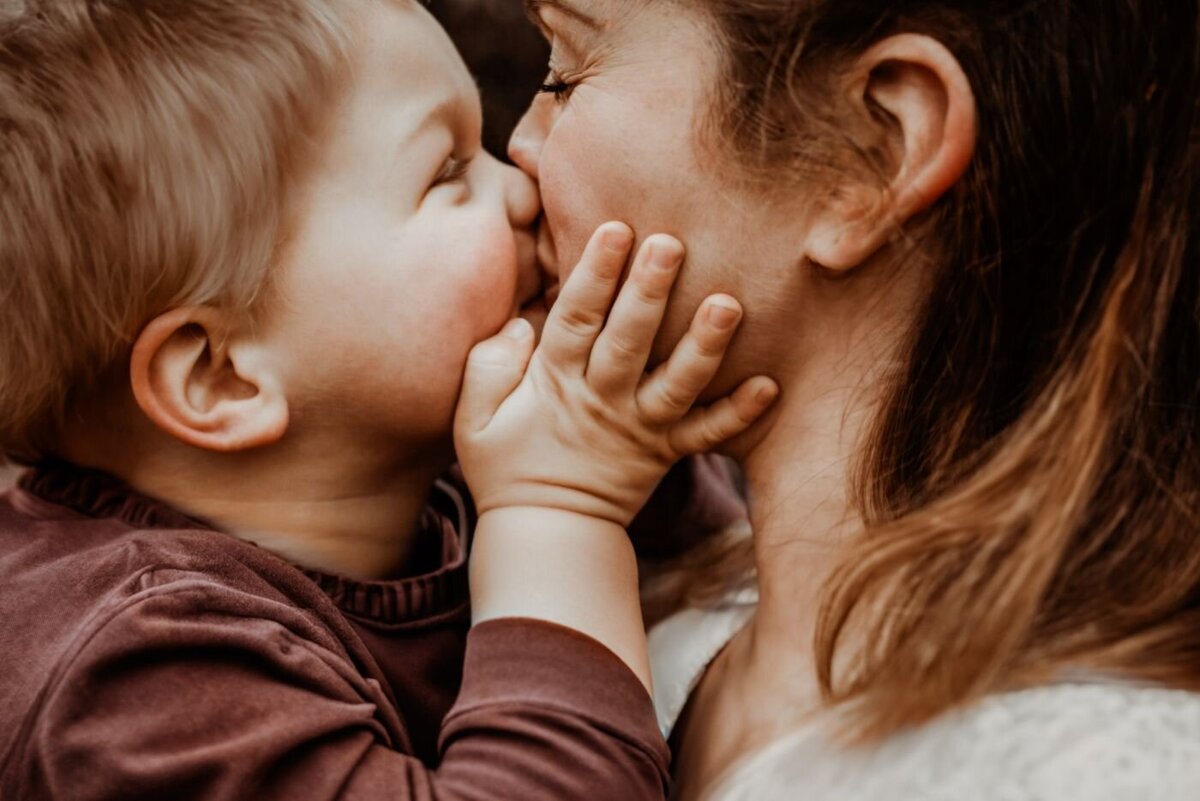 Gedetailleerde foto van een kind dat zijn moeder kust, met de nadruk op hun handen en gezichtsuitdrukkingen