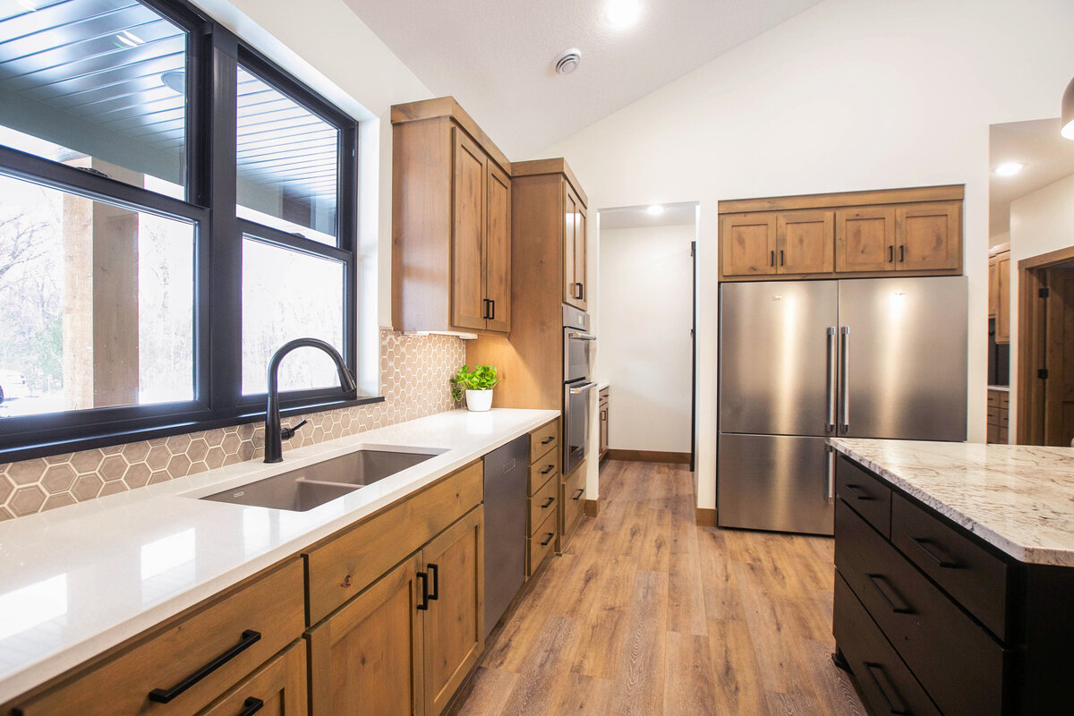 Open kitchen with dark cabinets, large island, and quartz countertops in an Elk River custom home