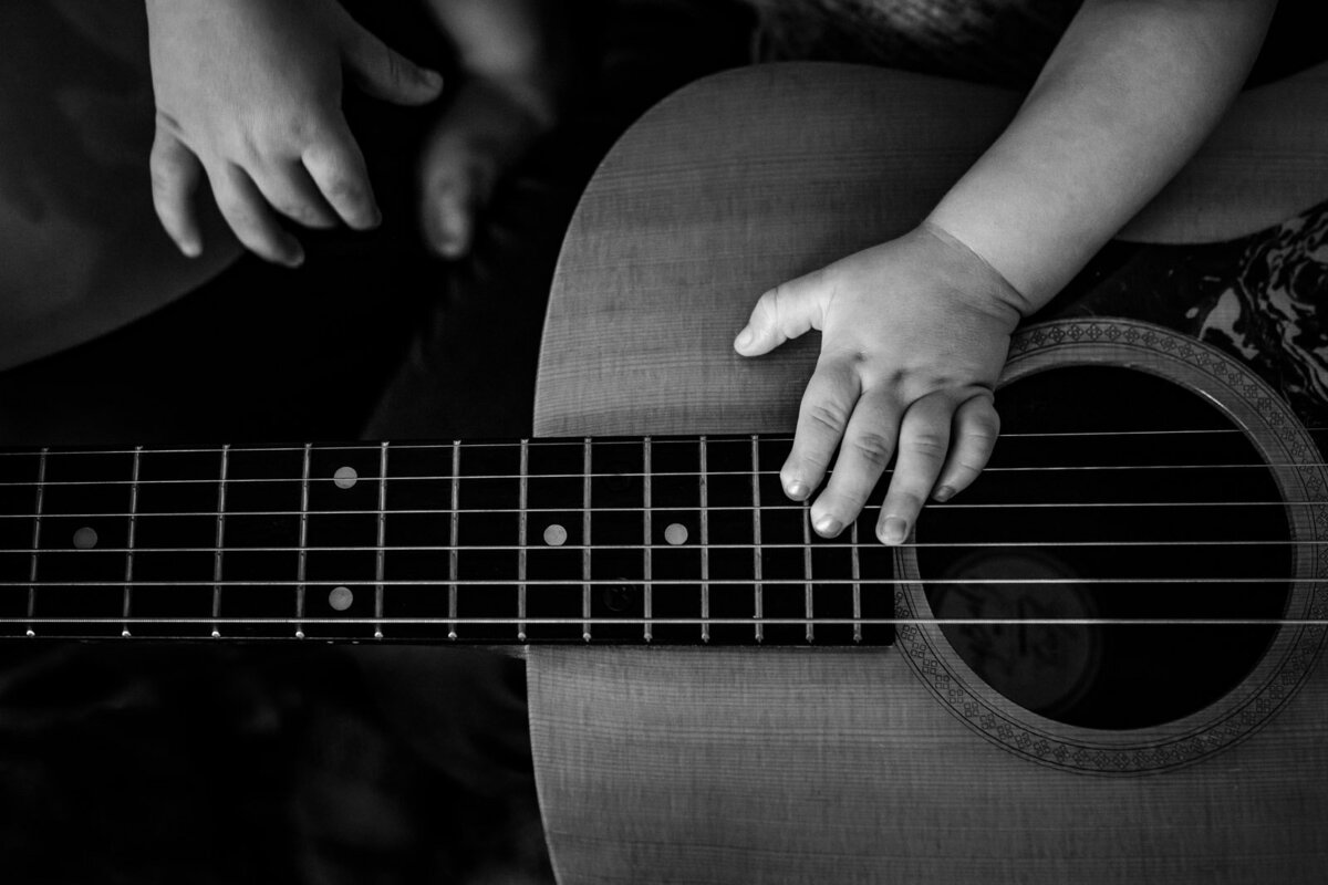 toddler's hand playing adult guitar