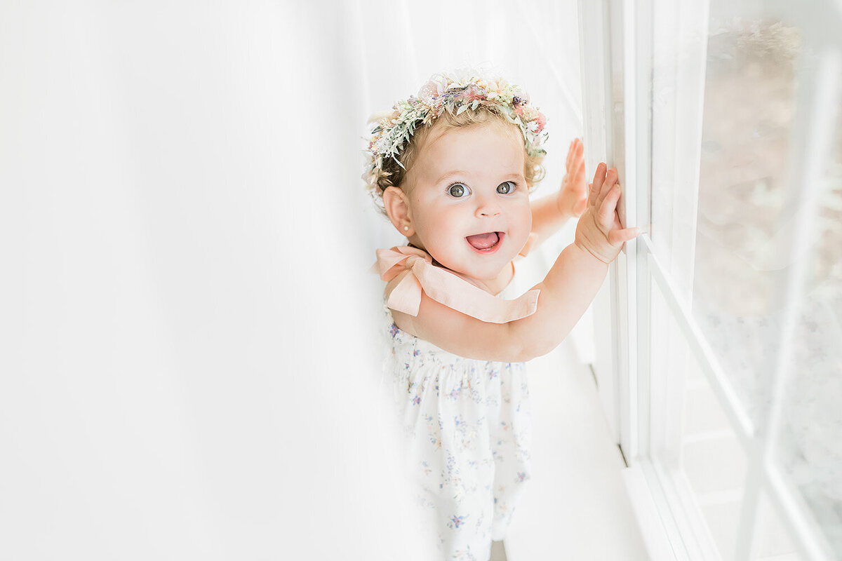 A baby girl in a flower crown posing for a family photographer in Destin, FL.