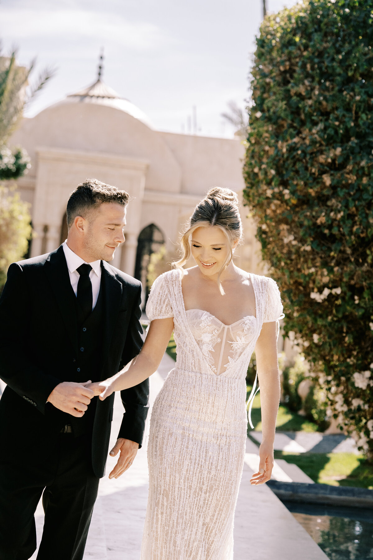 Bride in updo and short sleeved beaded wedding gown with bows and groom at Palais Namaskar Morocco for a destination wedding photographed by Italy photographer