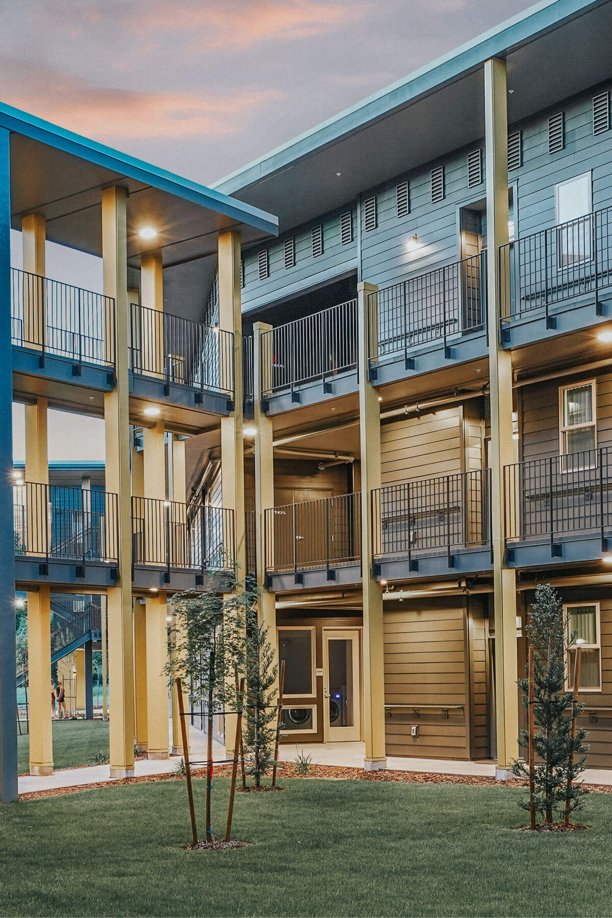 Modern multifamily courtyard at Lowden Lane in Redding, CA, featuring open walkways, green lawn, and structural columns.
