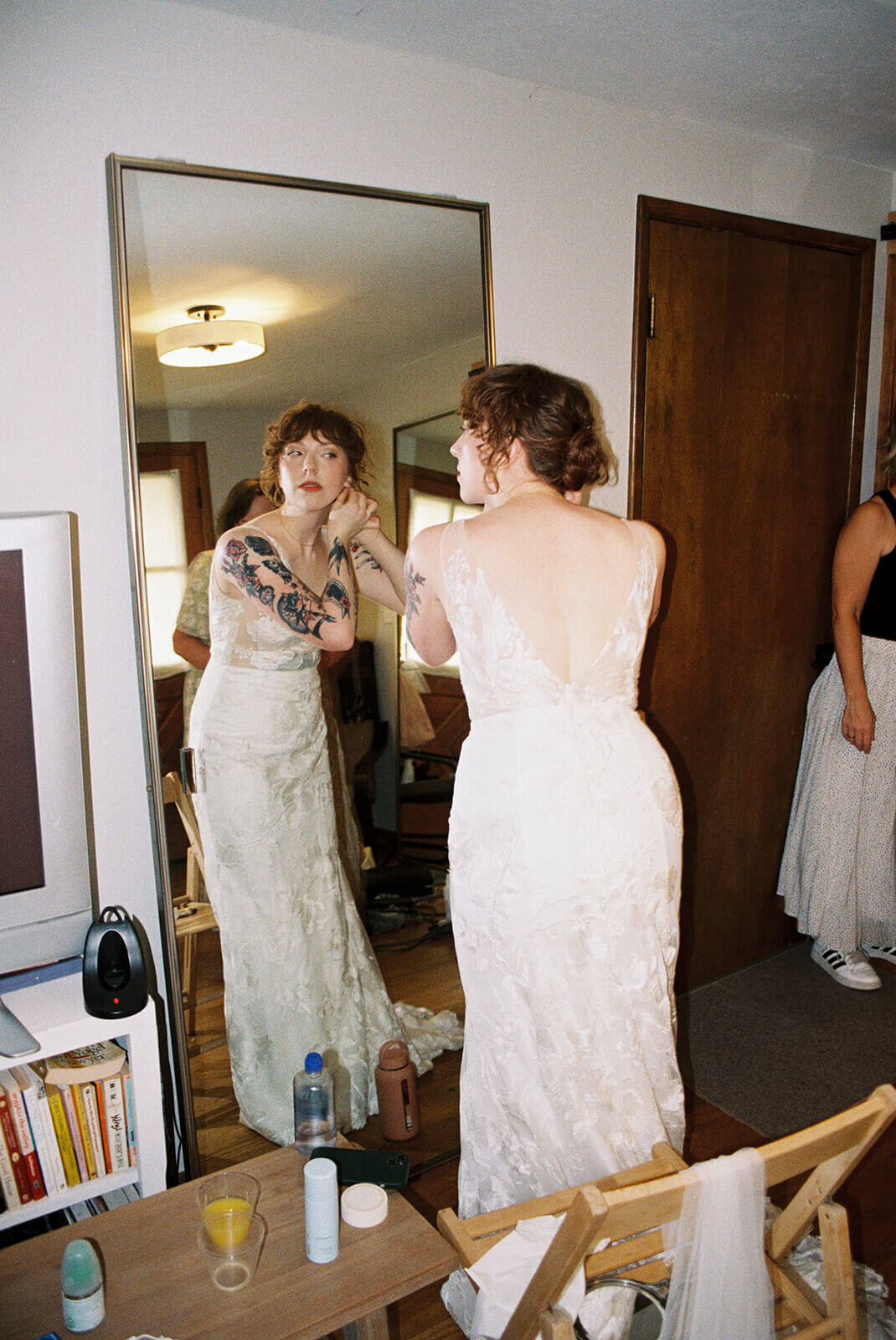 A bride in her wedding dress putting in earrings. 
