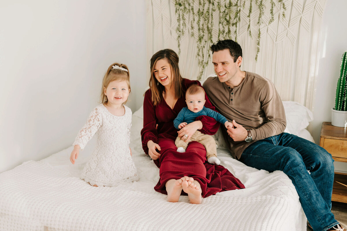 Branson MO family photographer captures family cuddling on bed during photography session
