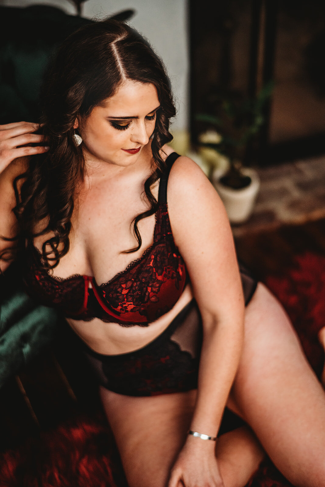 Baltimore photographers  captures in studio boudoir session with woman in a black and red lace pantie and bra set while holding her hair and looking down her shoulder