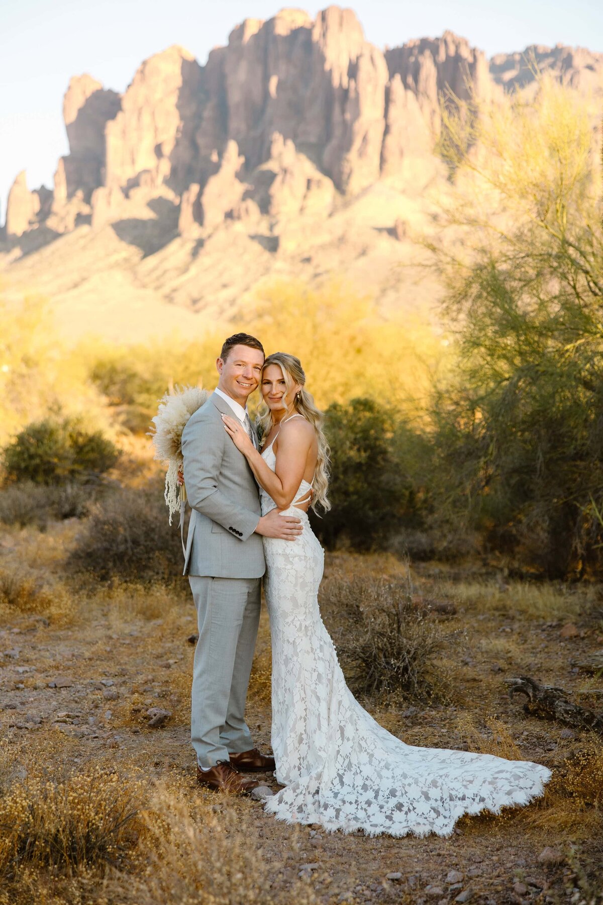 A bride and groom pose for a photo at Lost Dutchman State Park.