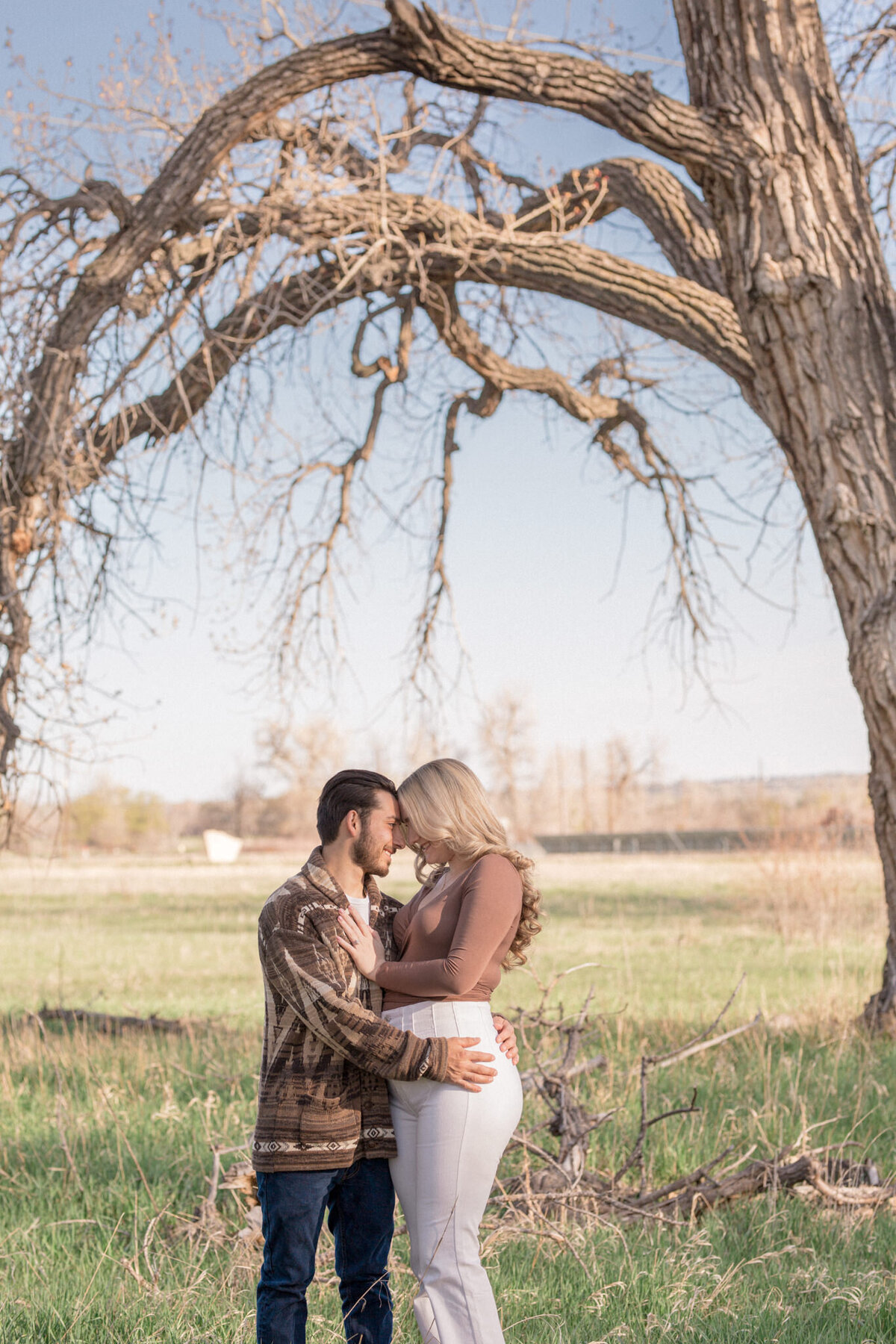 A couple embrace each other tightly in a field beside in East Boulder